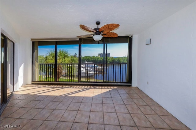 unfurnished sunroom with a water view and ceiling fan