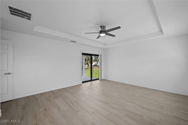 unfurnished room featuring ceiling fan, a raised ceiling, and light hardwood / wood-style flooring