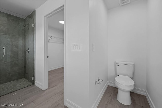 bathroom with toilet, hardwood / wood-style floors, and walk in shower