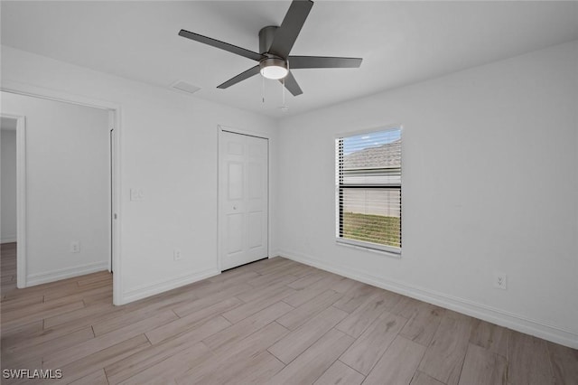 unfurnished bedroom featuring ceiling fan, light wood-type flooring, and a closet