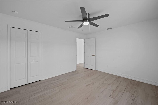 unfurnished bedroom featuring light hardwood / wood-style floors, a closet, and ceiling fan