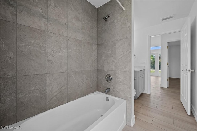 bathroom featuring tiled shower / bath combo and vanity