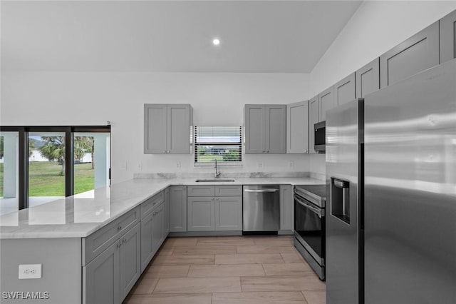 kitchen with sink, plenty of natural light, kitchen peninsula, and appliances with stainless steel finishes