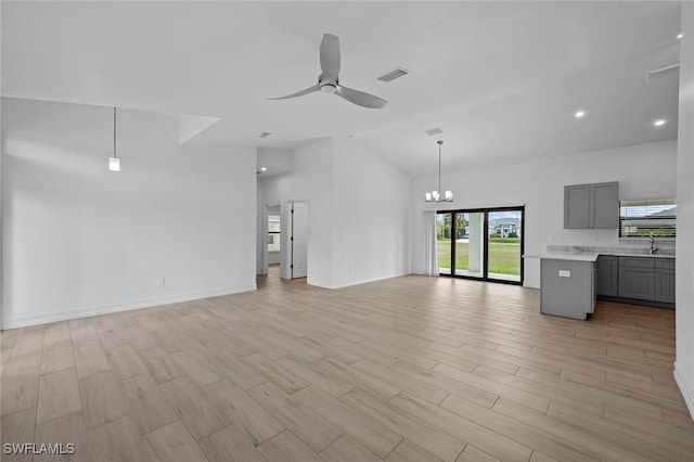 unfurnished living room featuring high vaulted ceiling, sink, light hardwood / wood-style floors, and ceiling fan with notable chandelier