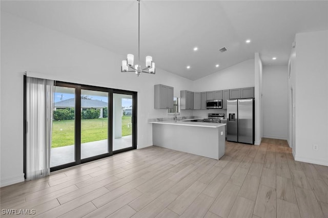 kitchen featuring gray cabinetry, stainless steel appliances, a notable chandelier, decorative light fixtures, and kitchen peninsula