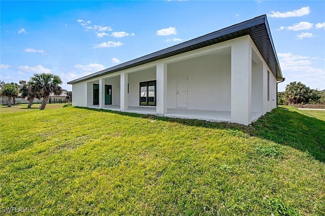 back of house featuring a lawn and a patio area