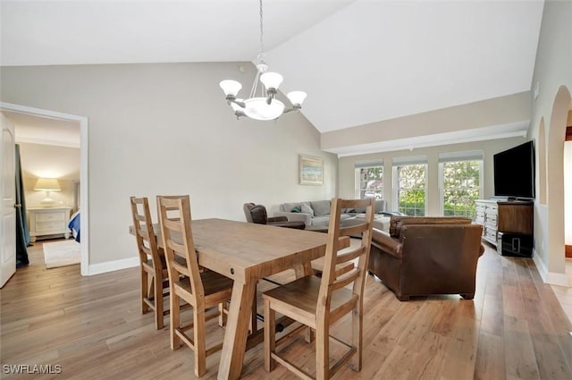 dining space with an inviting chandelier, vaulted ceiling, and light hardwood / wood-style flooring