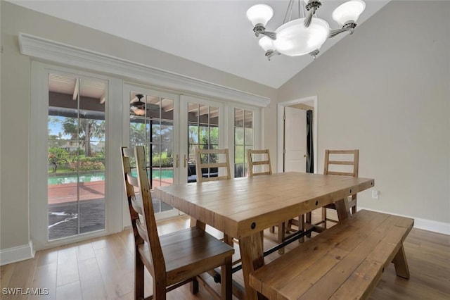 dining area with a notable chandelier, wood-type flooring, french doors, and vaulted ceiling