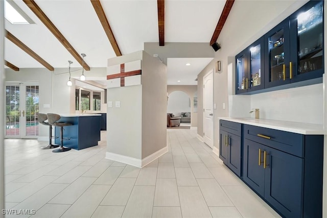 kitchen with beam ceiling, decorative light fixtures, blue cabinetry, and a kitchen bar