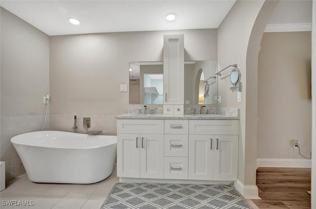 bathroom featuring a washtub, vanity, hardwood / wood-style floors, and tile walls