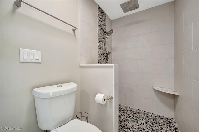 bathroom featuring a tile shower and toilet