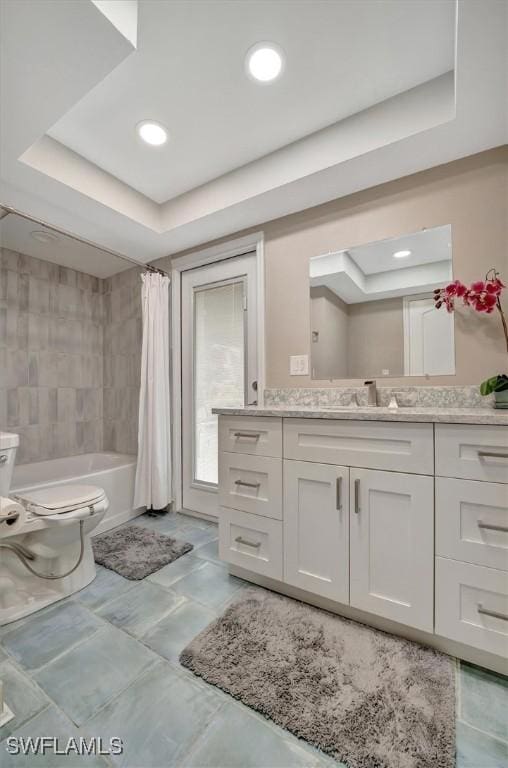 full bathroom featuring shower / tub combo with curtain, vanity, a raised ceiling, and toilet