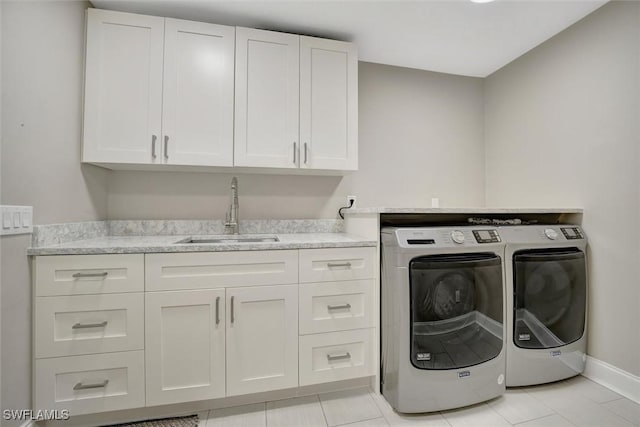 clothes washing area with sink, light tile patterned floors, cabinets, and washing machine and clothes dryer