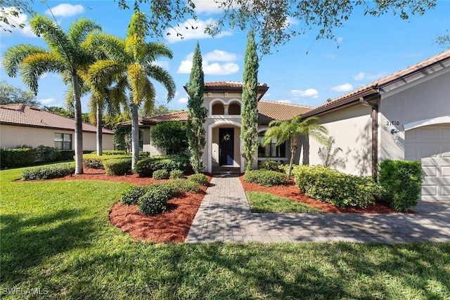 mediterranean / spanish-style house featuring a garage and a front lawn