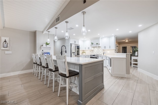 kitchen with stainless steel appliances, white cabinets, light countertops, hanging light fixtures, and a center island