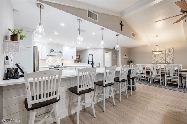 kitchen featuring visible vents, white cabinetry, light countertops, decorative backsplash, and decorative light fixtures