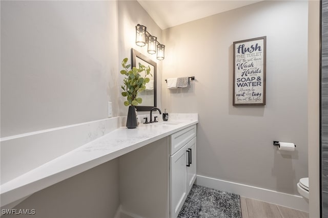 bathroom with vanity, toilet, and baseboards