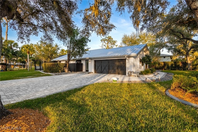 view of front facade with a front yard, decorative driveway, metal roof, and an attached garage