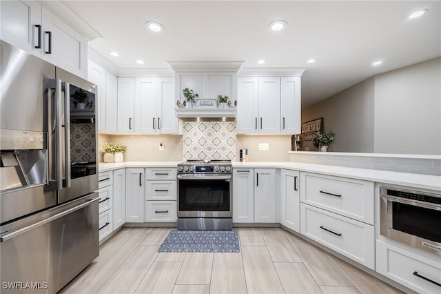 kitchen with stainless steel appliances, light countertops, decorative backsplash, white cabinets, and premium range hood