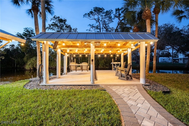 patio terrace at dusk featuring a gazebo and a lawn