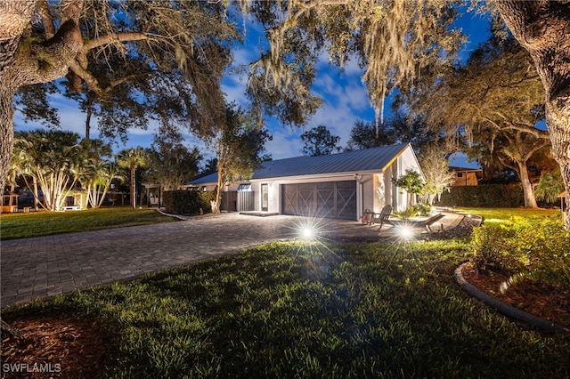 view of front facade featuring a garage, metal roof, decorative driveway, and a front yard