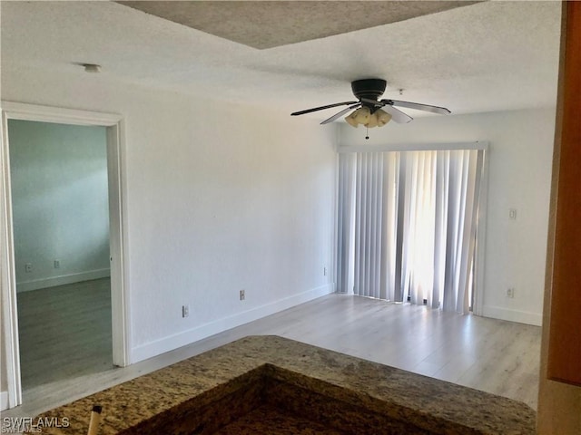 unfurnished room with a textured ceiling, ceiling fan, and light hardwood / wood-style flooring