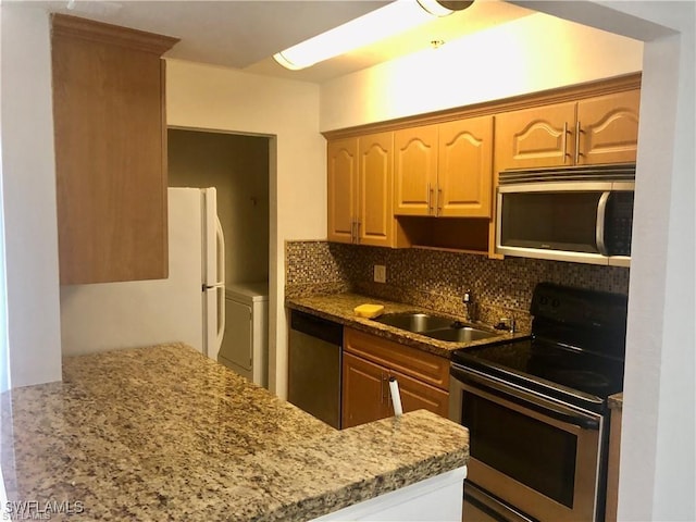 kitchen featuring washer / dryer, sink, backsplash, stainless steel appliances, and light stone countertops