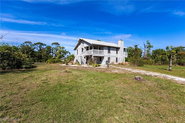 rear view of house featuring stairs and a lawn