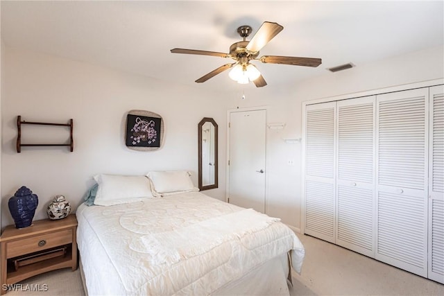 bedroom featuring ceiling fan, a closet, visible vents, and light colored carpet