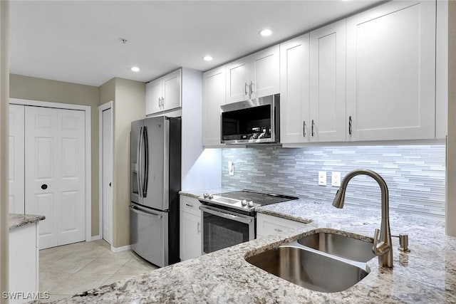 kitchen featuring sink, backsplash, stainless steel appliances, light stone countertops, and white cabinets