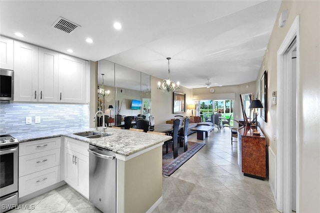 kitchen featuring stainless steel appliances, kitchen peninsula, sink, and white cabinets