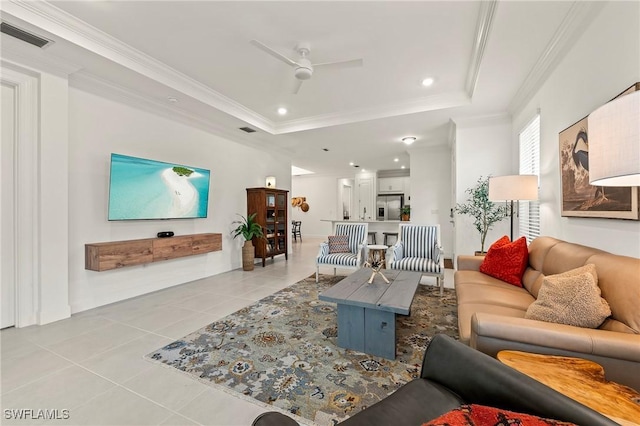 living room with light tile patterned flooring, ceiling fan, crown molding, and a tray ceiling