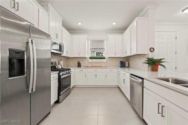 kitchen with appliances with stainless steel finishes, white cabinets, decorative backsplash, light tile patterned floors, and crown molding