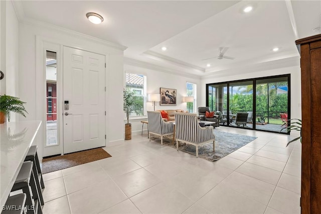 entrance foyer with crown molding, a healthy amount of sunlight, a tray ceiling, and light tile patterned floors