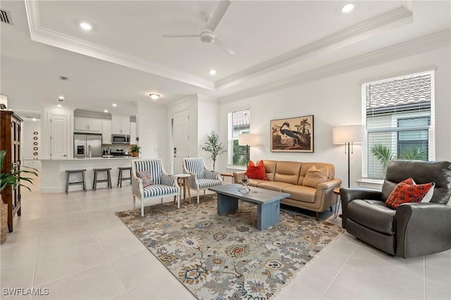 tiled living room with crown molding, a tray ceiling, and ceiling fan