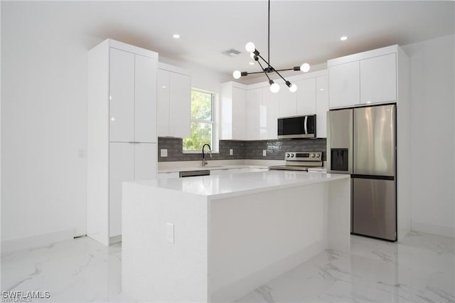 kitchen featuring sink, white cabinetry, decorative light fixtures, appliances with stainless steel finishes, and a kitchen island