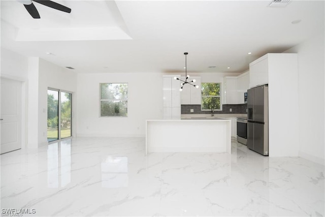 kitchen with stove, a center island, stainless steel refrigerator with ice dispenser, white cabinets, and decorative light fixtures