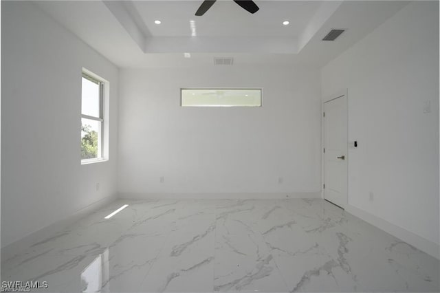 empty room featuring ceiling fan and a tray ceiling