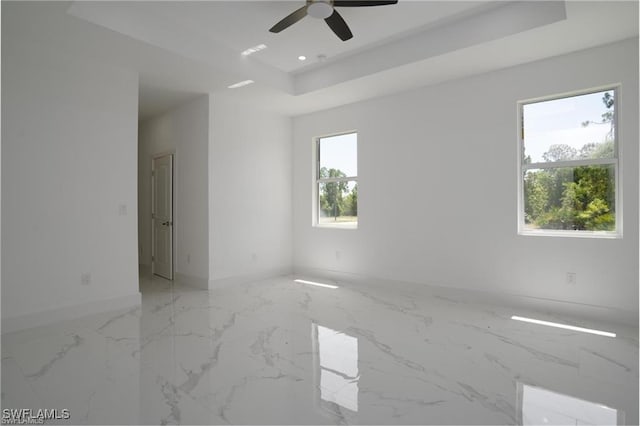 spare room featuring a tray ceiling and ceiling fan