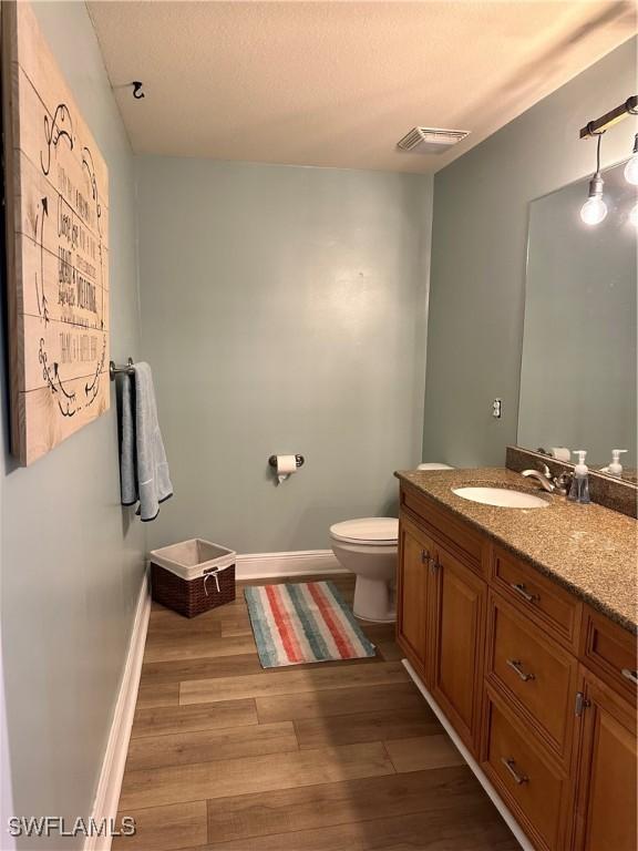 bathroom featuring vanity, wood-type flooring, and toilet