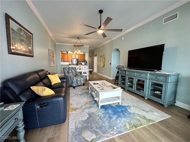 living room featuring crown molding, wood-type flooring, and ceiling fan with notable chandelier