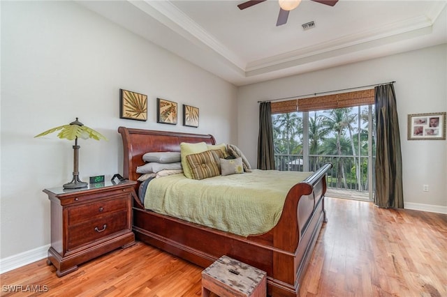 bedroom with access to outside, ceiling fan, a tray ceiling, crown molding, and light wood-type flooring