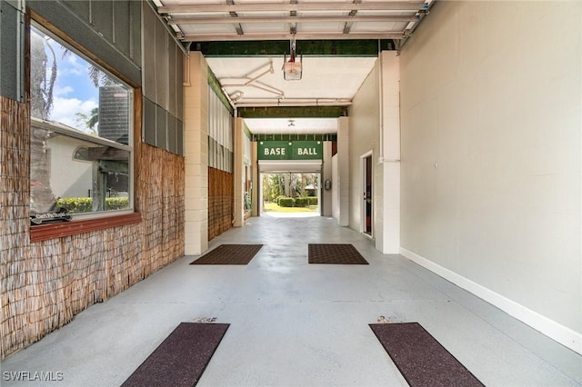 hall featuring a high ceiling, brick wall, and concrete floors