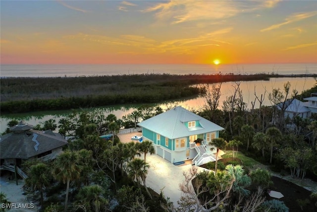 aerial view at dusk featuring a water view