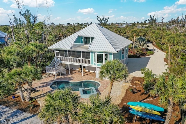 rear view of property with a patio area, a pool with hot tub, and a sunroom