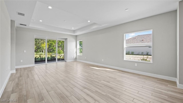 unfurnished room with a tray ceiling and light hardwood / wood-style flooring