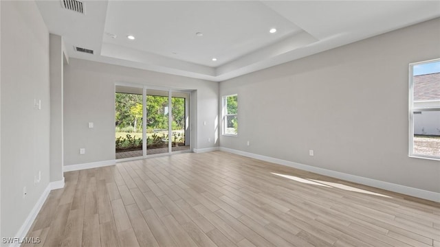 unfurnished room with a raised ceiling and light hardwood / wood-style flooring