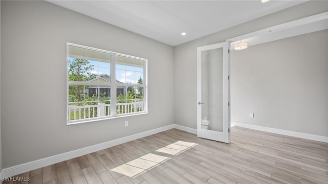 empty room featuring french doors and light hardwood / wood-style flooring