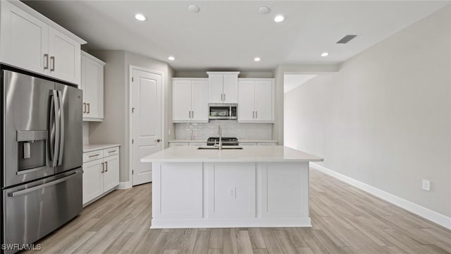 kitchen with white cabinetry, appliances with stainless steel finishes, sink, and a center island with sink