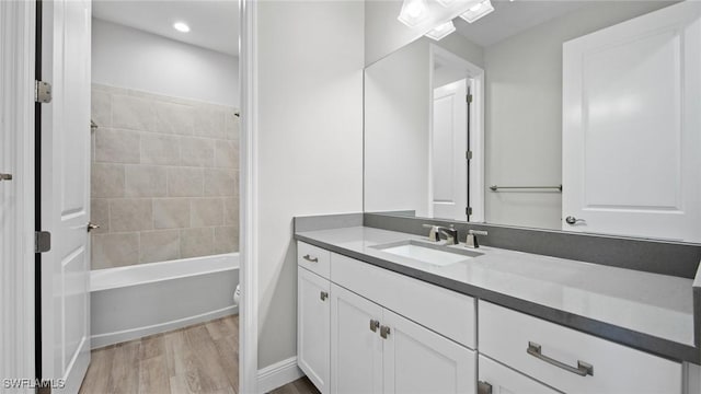 full bathroom featuring vanity, tiled shower / bath combo, wood-type flooring, and toilet